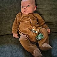 Noé participe au concours pour gagner de l'argent avec cette photo : baby, infant, onesie, pacifier, toy, couch, furniture, indoor, child, person, seat, relaxing, cute, expression, clothing, footed_pajamas, sitting, home, cozy, soft