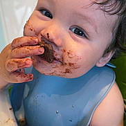 Jacobie joined the competition — help win amazing prizes! baby, blue_bib, child, chocolate, closeup, curly_hair, cute, eating, face, food, hands, happy, highchair, indoor, infant, messy, portrait, skin, smiling, toddler
