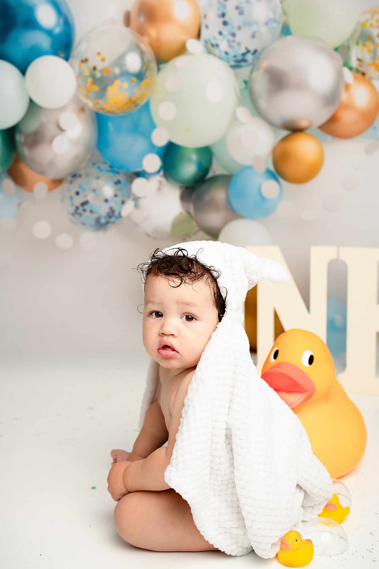 Jacobie is registered to the contest to win money with this photo: baby, child, towel, bunny_ears, rubber_duck, balloons, decor, curly_hair, cute, sitting, playful, studio, background, soft_texture, indoors, portrait, toy, yellow, white, celebration