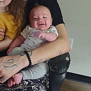 Storm joined the competition — help win amazing prizes! man, baby, child, toddler, smiling, hat, tattoo, bracelet, armchair, onesie, pants, wood_floor, indoor, portrait, holding, happy, curly_hair, seat, clothing, face