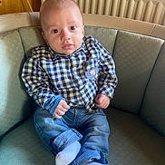 Malone participe au concours pour gagner de l'argent avec cette photo : baby, child, infant, plaid_shirt, jeans, socks, couch, furniture, indoors, radiator, wood_paneling, face, person, seated, curious, casual_clothing, home, portrait, young_child, comfortable