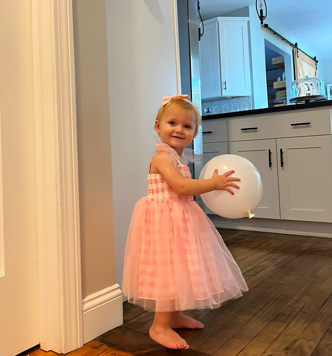 Saylor is registered to the contest to win money with this photo: baby_toddler_clothing, blond, cabinetry, day_dress, drawer, dress, flooring, formal_wear, fun, happy, hardwood, interior_design, joy, kitchen, major_appliance, one_piece_garment, person, shoulder, smile, toddler