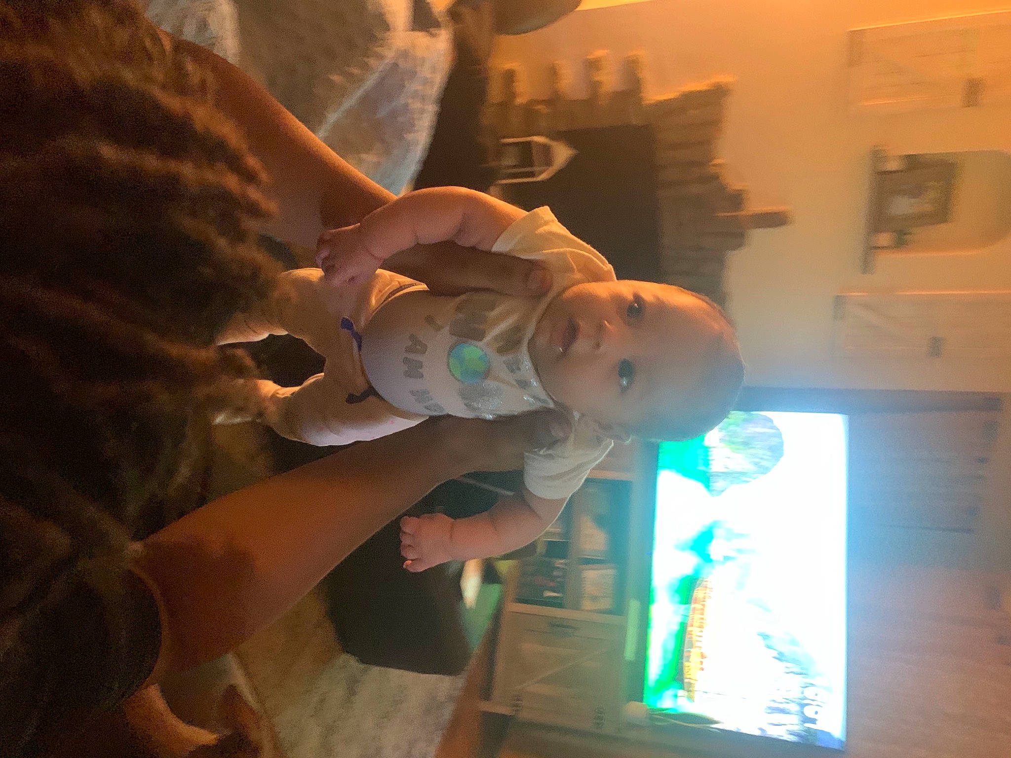 Jalani is registered to the contest to win money with this photo: baby, child, display_device, ear, event, finger, fun, gesture, hat, lighting_accessory, person, reflection, room, sitting, smile, space, t_shirt, television_set, toddler, visual_arts