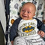 baby, smiling, batman, shirt, clothing, baby_seat, pattern, elephant, flower, happy, infant, cute, child, indoor, person, sitting, comfortable, playful, young, portrait