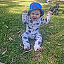 baby, barefoot, bucket_hat, cartoon_print, child, clothing, daylight, grass, greenery, happy, hat, nature, onesie, outdoor, park, person, playful, sitting, smiling, sunlight