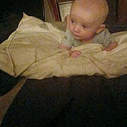 Emmett is registered to the contest to win money with this photo: baby, blanket, child, cozy, curious, cushion, dim_light, face, furniture, hands, head, home, indoor, infant, looking_away, person, portrait, soft_lighting, toddler, young_child