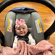 Tenley is registered to the contest to win money with this photo: baby, blanket, car_seat, child, clothing, comfort, cute, happy, headband, indoors, infant, person, pink_bow, portrait, safety_harness, seat, smile, soft_texture, toddler, wood_floor
