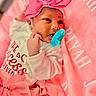 baby, infant, pacifier, pink_bow, pink_blanket, pink_tutu, white_onesie, newborn, cute, portrait, child, face, hand, soft_texture, fabric, resting, laying_down, indoor, closeup, adorable