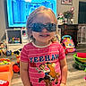 Barbie Rae joined the competition — help win amazing prizes! child, toddler, portrait, smiling, sunglasses, pink_shirt, striped_clothing, indoor, playroom, toys, television, furniture, home, standing, blonde_hair, face, happy, colorful, family_room, photograph