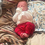 Brad joined the competition — help win amazing prizes! baby, newborn, sleeping, pacifier, blanket, pillow, red_pants, white_shirt, foot, indoor, cozy, patterned_blanket, infant, resting, cute, child, soft_lighting, portrait, comfort, peaceful