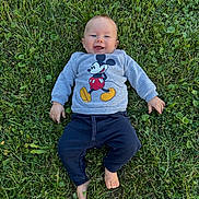 Sasha participe au concours pour gagner de l'argent avec cette photo : baby, child, grass, outdoor, smiling, happy, clothing, sweatshirt, pants, barefoot, greenery, nature, cute, infant, person, lying_down, casual_wear, daylight, playful, mickey_mouse