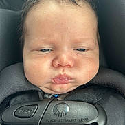 Koelson is registered to the contest to win money with this photo: baby, infant, face, car_seat, harness, straps, pout, chubby_cheeks, black, closeup, child, person, seatbelt, safety, expression, cute, young, head, indoors, portrait