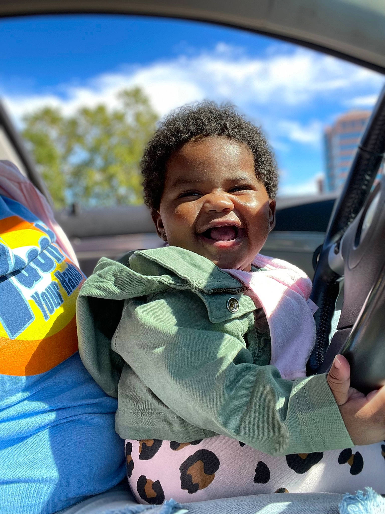 Aubrey is registered to the contest to win money with this photo: auto_part, automotive_exterior, automotive_mirror, fun, grass, happy, jacket, leisure, motor_vehicle, person, personal_protective_equipment, photograph, rear_view_mirror, recreation, sky, steering_wheel, toddler, tree, vehicle_door, white