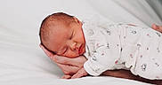Romy participe au concours pour gagner de l'argent avec cette photo : newborn, baby, sleeping, hand, white_bed, onesie, floral_pattern, soft_lighting, peaceful, infant, close_up, portrait, human, rest, comfort, cute, tender, care, parent, cozy