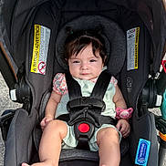 Camila is registered to the contest to win money with this photo: baby, car_seat, child, infant, seatbelt, pacifier, pigtails, outdoor, footwear_free, clothing, safety, child_safety, stroller, black_straps, cute, small_hands, small_feet, pink, gray, fabric