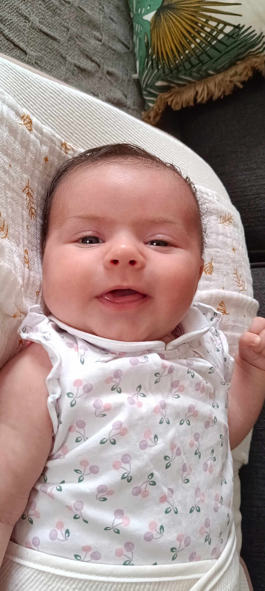 Leonie participe au concours pour gagner de l'argent avec cette photo : baby, child, smiling, infant, white_dress, patterned_clothing, blanket, cushion, green_pillow, indoor, cute, happy, person, face, head, young_child, soft_texture, resting, closeup, comfortable