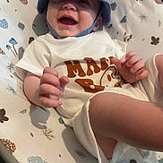 Hunter Jay is registered to the contest to win money with this photo: baby, child, smiling, hat, blue_hat, white_clothing, patterned_cushion, leaves_pattern, pinecone_pattern, happy, infant, cute, hand, face, toddler, indoors, lying_down, apparel, closeup, playful