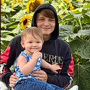 Azalea joined the competition — help win amazing prizes! child, young_adult, smiling, sunflower, flower_field, outdoor, hoodie, jeans, wicker_chair, nature, greenery, happy, casual_clothing, portrait, family, holding, sitting, daylight, plants, people