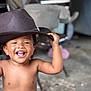 Paisley joined the competition — help win amazing prizes! child, toddler, smiling, hat, bare_chest, happy, portrait, indoor, candid, joyful, cute, baby_teeth, curly_hair, holding_hat, furniture, blurred_background, person, playful, skin, headwear
