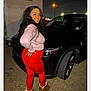 woman, smiling, night, car, black_car, red_leggings, pink_sweater, boots, streetlight, outdoor, posing, long_hair, asphalt, vehicle, casual_clothing, side_view, urban, nighttime, person, portrait