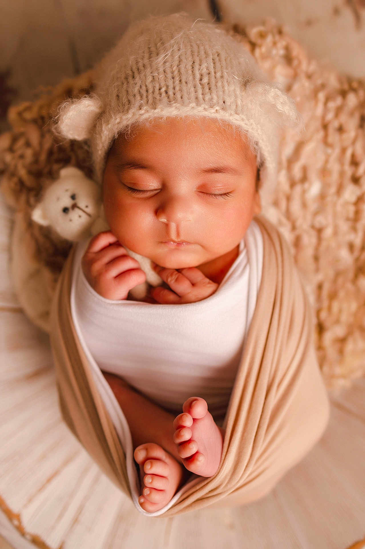 Cyrus is registered to the contest to win money with this photo: baby, sleeping, newborn, swaddled, hat, knit, stuffed_animal, toes, soft_lighting, cozy, cute, infant, peaceful, wrapped, child, portrait, closeup, warm_colors, hands, face