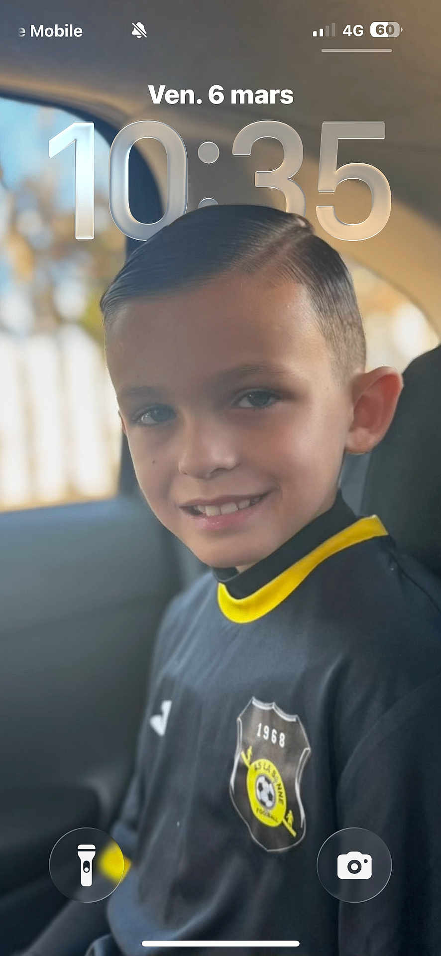 Aaron a rejoint le concours — aidez-le/la à gagner de superbes lots ! child, boy, smiling, portrait, car_interior, seat, sports_jersey, soccer_badge, short_hair, ear, eyes, teeth, closeup, natural_light, blurred_background, window, headrest, lock_screen, timestamp_overlay, casual