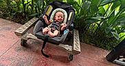 Remington is registered to the contest to win money with this photo: baby, baby_seat, baby_smiling, car_seat, child, cute, daylight, floor, green_plants, happy_baby, infant, leafy_plants, nature, outdoor, red_tiles, seat_belt, sunlight, toddler, wheeled_platform, wooden_platform