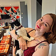 Taiga participe au concours pour gagner de l'argent avec cette photo : woman, cat, indoor, smiling, bow_tie, tattoo, red_dress, watch, bracelet, chair, table, geometric_wall, decor, floor, plant, television, holiday_decor, happy, person, holding