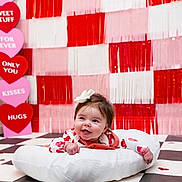 Clara joined the competition — help win amazing prizes! baby, smile, infant, cushion, bow, red, pink, hearts, valentines_day, floor, checkered_floor, happy, cute, background, decoration, child, portrait, indoors, clothing, face