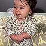 baby, infant, pajamas, floral_pattern, smiling, hands_clasped, cushion, giraffe_pattern, indoor, carpet, child, cute, portrait, young, seated, soft_lighting, happy, face, person, cozy