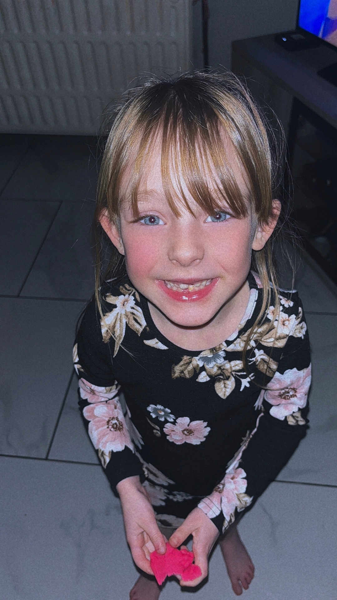 Siana a rejoint le concours — aidez-le/la à gagner de superbes lots ! child, girl, smile, floral_dress, barefoot, indoor, tile_floor, holding_object, pink_object, long_sleeves, light_hair, bangs, happy, portrait, person, cute, young, standing, looking_up, casual
