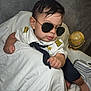 baby, child, sunglasses, pilot_uniform, white_cloth, globe, suitcase, indoor, portrait, cute, fashion, accessory, person, infant, hand, foot, black_hair, tie, bracelet, seat