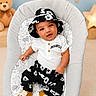 baby, infant, child, hat, clothing, black_and_white, floral_pattern, baby_seat, teddy_bear, nursery, decor, stars, clouds, shoes, smiling, portrait, indoor, cute, comfortable, happy