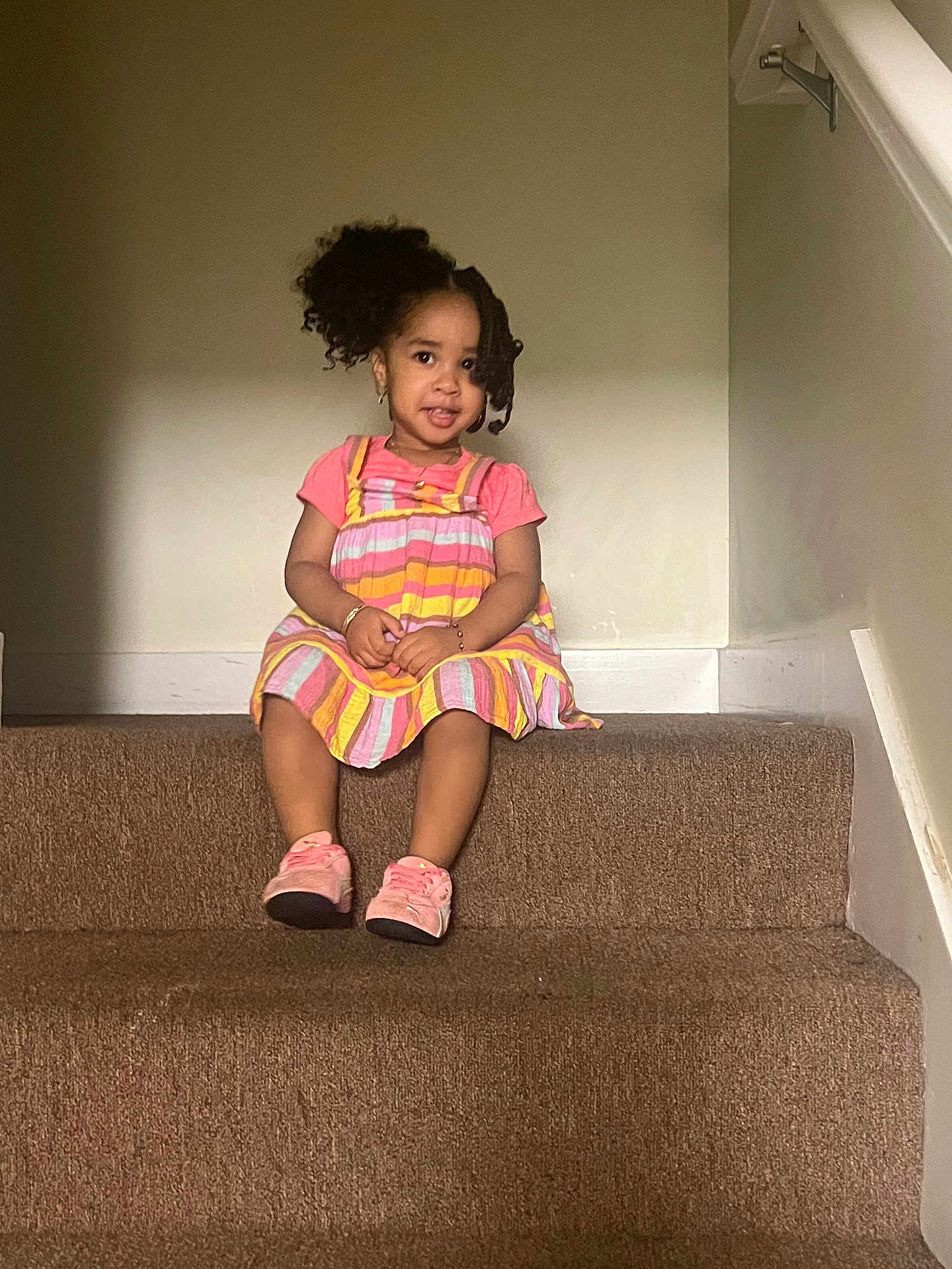 Analina is registered to the contest to win money with this photo: child, toddler, girl, stairs, carpet, dress, pink_shoes, curly_hair, indoor, smiling, sitting, young_child, playful, fashion, casual, person, portrait, accessories, cute, happy
