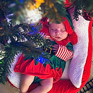 Iylah-Jane is registered to the contest to win money with this photo: baby, sleeping, christmas, elf_costume, holiday, tree, christmas_tree, lights, decorations, red, green, white, cushion, basket, wood_floor, infant, peaceful, festive, child, holiday_season