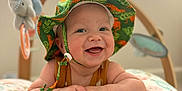 Owen joined the competition — help win amazing prizes! baby, child, hat, green_hat, smiling, happy, cushion, dinosaur_pattern, infant, lying_down, toy, elephant_toy, indoor, window_blinds, natural_light, cute, portrait, colorful, playtime, baby_clothing