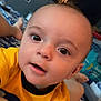 Asher is registered to the contest to win money with this photo: baby, child, face, eyes, yellow_shirt, bed, blanket, indoor, person, portrait, closeup, expression, curious, skin, head, mouth, human, room, television, foot