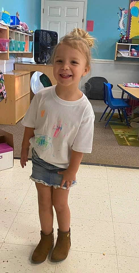 Finley is registered to the contest to win money with this photo: child, fun, hairstyle, happy, human_leg, joint, joy, leg, leisure, organ, person, photograph, shipping_box, shorts, sleeve, smile, snapshot, standing, t_shirt, table