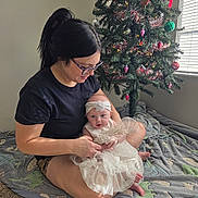 Amelia joined the competition — help win amazing prizes! woman, baby, indoor, christmas_tree, blanket, dress, headband, glasses, carpet, window, sunlight, holiday, decorations, celebration, smile, family, mother, child, portrait, seated