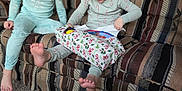 Joseph is registered to the contest to win money with this photo: child, children, pajamas, gift, present, couch, carpet, indoor, happy, smile, unwrapping, holiday, patterned_fabric, barefoot, glasses, living_room, excitement, family, playful, cozy