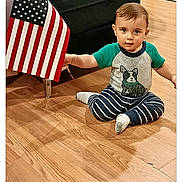 Rayn joined the competition — help win amazing prizes! child, toddler, baby, sitting, floor, hardwood_floor, american_flag, chair, striped_pajamas, shirt, socks, indoor, home, furniture, portrait, looking_at_camera, serious_expression, short_hair, photograph, social_media_screen
