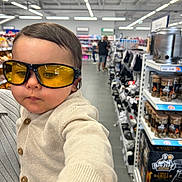 Isaac participe au concours pour gagner de l'argent avec cette photo : aisle, baby, buttoned_cardigan, casual, child, clothing, face, groceries, hand, head, indoor, person, portrait, products, shelf, shopping_aisle, store, sunglasses, toddler, yellow_glasses