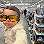 Isaac participe au concours pour gagner de l'argent avec cette photo : aisle, baby, buttoned_cardigan, casual, child, clothing, face, groceries, hand, head, indoor, person, portrait, products, shelf, shopping_aisle, store, sunglasses, toddler, yellow_glasses