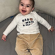 Isaac a rejoint le concours — aidez-le/la à gagner de superbes lots ! baby, infant, smile, happy, face, child, clothing, pants, shirt, sock, striped_sock, pillow, bed, blanket, indoor, cute, portrait, lying_down, person, young_child
