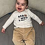 baby, infant, smile, happy, face, child, clothing, pants, shirt, sock, striped_sock, pillow, bed, blanket, indoor, cute, portrait, lying_down, person, young_child