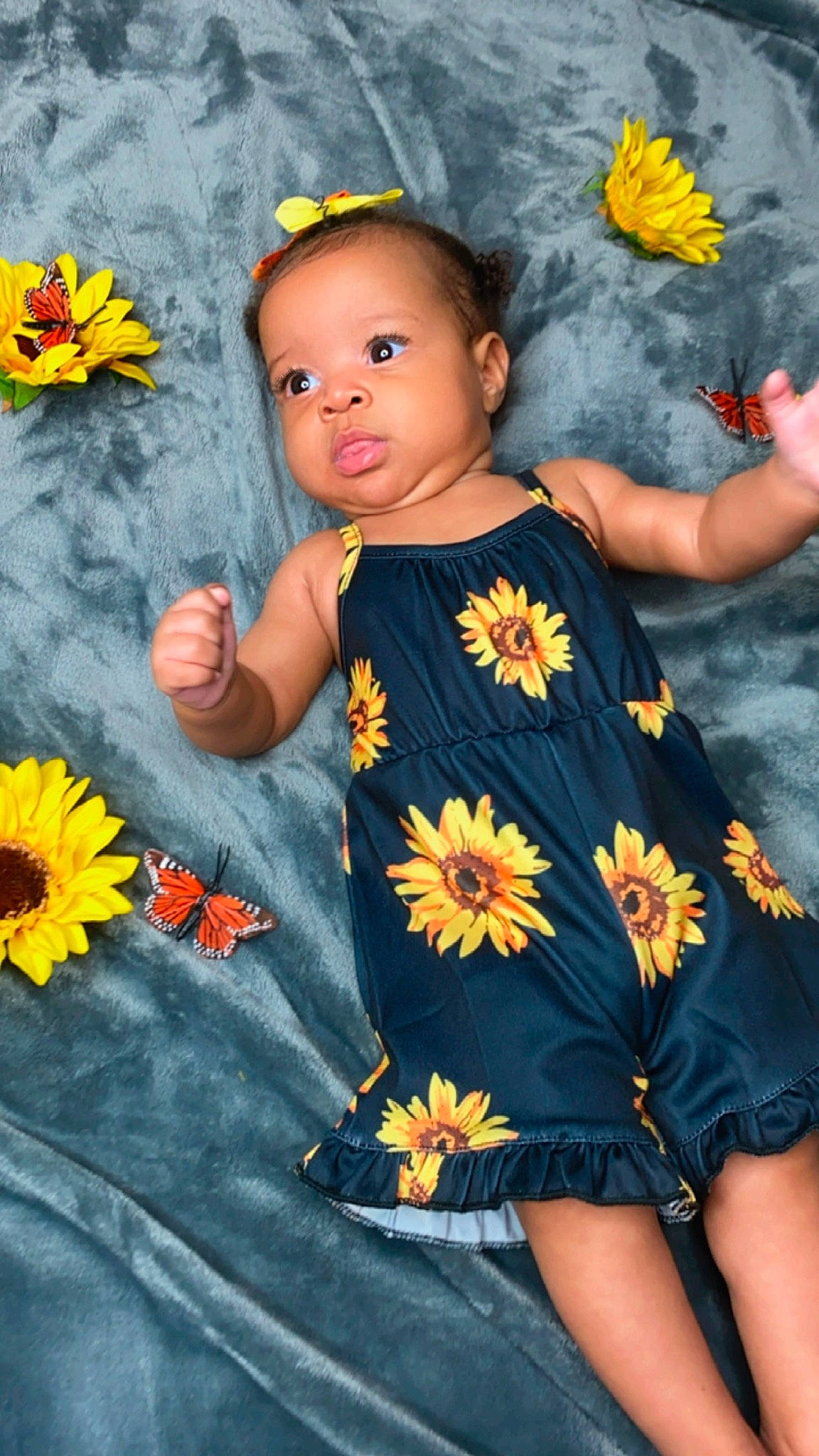 Ily is registered to the contest to win money with this photo: arm, baby_toddler_clothing, blue, child, dress, finger, flower, hand, happy, head, leaf, orange, people_in_nature, person, petal, plant, skin, summer, textile, toddler