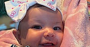 Alaiyah is registered to the contest to win money with this photo: baby, child, smiling, headband, bow, blanket, indoor, portrait, cute, happy, infant, clothing, person, skin, face, arm, soft, mural, mountain, background