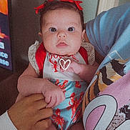 Alaiyah is registered to the contest to win money with this photo: baby, infant, child, red_bows, lobster_outfit, people, hands, indoor, person, cute, clothing, portrait, holding, face, skin, expression, young, colorful, adult_hands, closeup