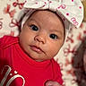 baby, infant, close_up, headband, bow, red_clothing, polka_dots, face, cute, portrait, newborn, hand, soft_focus, background_blur, expression, child, skin, eyes, person, indoors