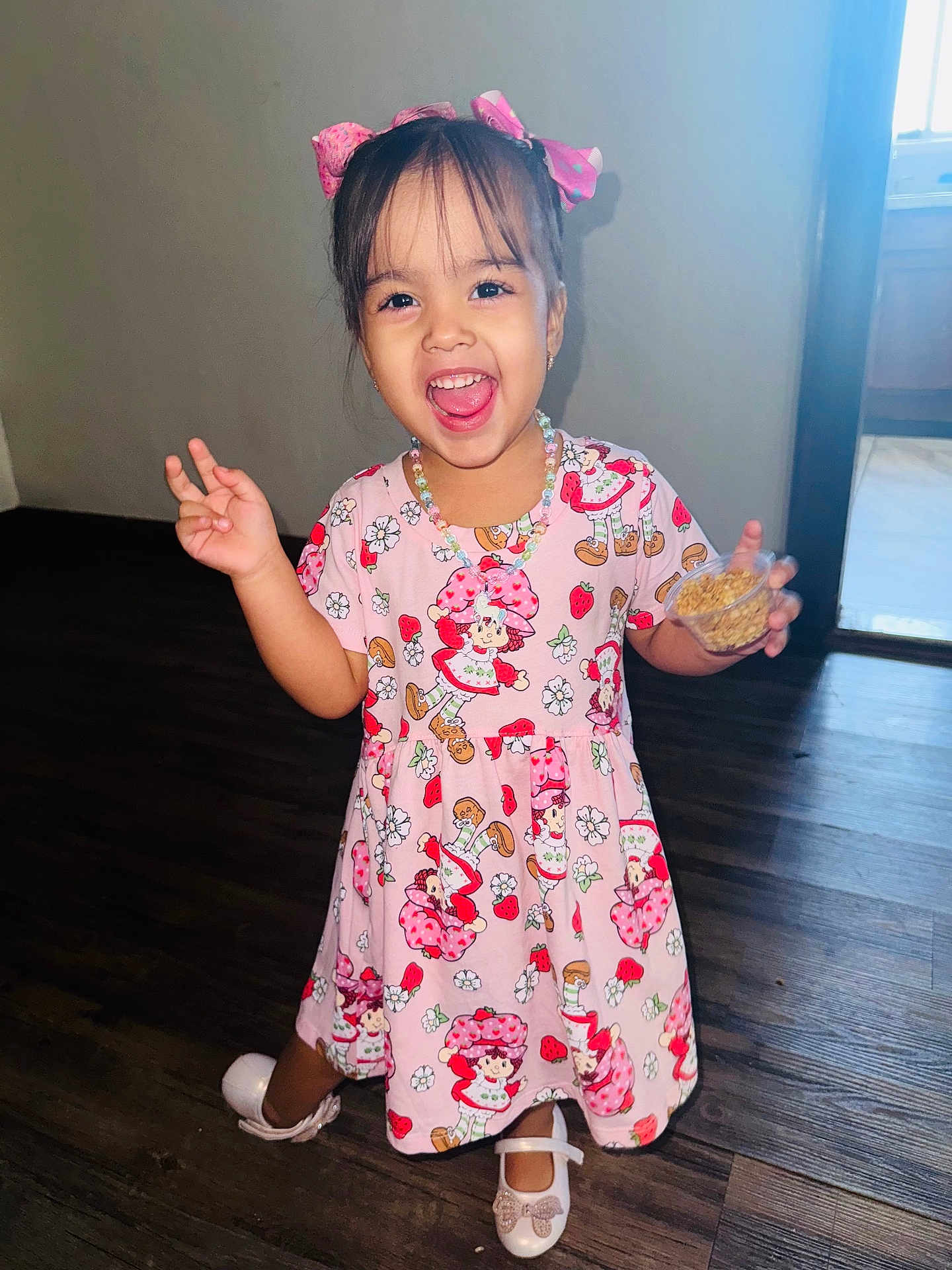 Dashley joined the competition — help win amazing prizes! child, girl, smiling, indoor, dress, pink, playful, snack, floor, wooden_floor, hair_bow, happy, small_cup, footwear, portrait, person, cute, jewelry, light, window